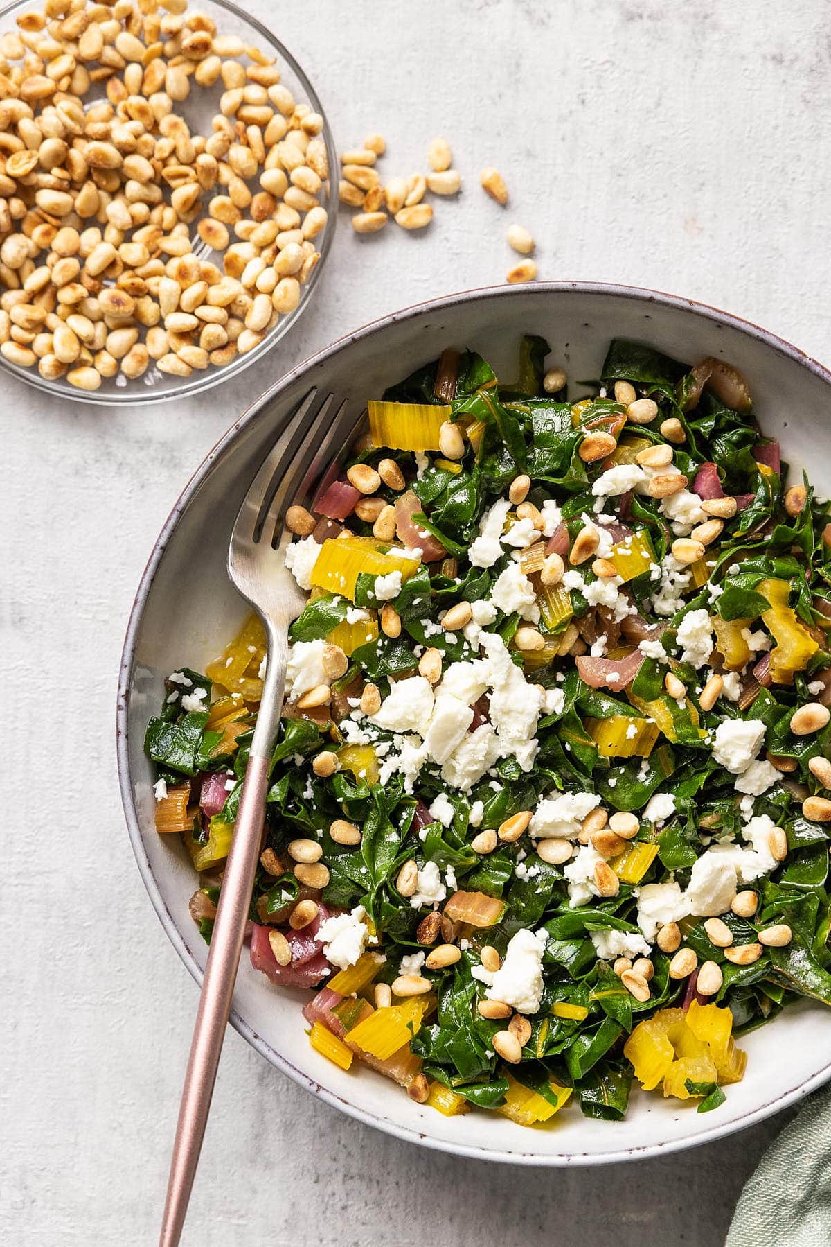 Bowl with swiss chard with feta and topped with pine nuts