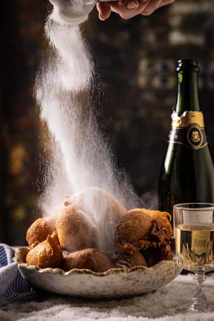 Dutch doughnuts being dusted with icing sugar