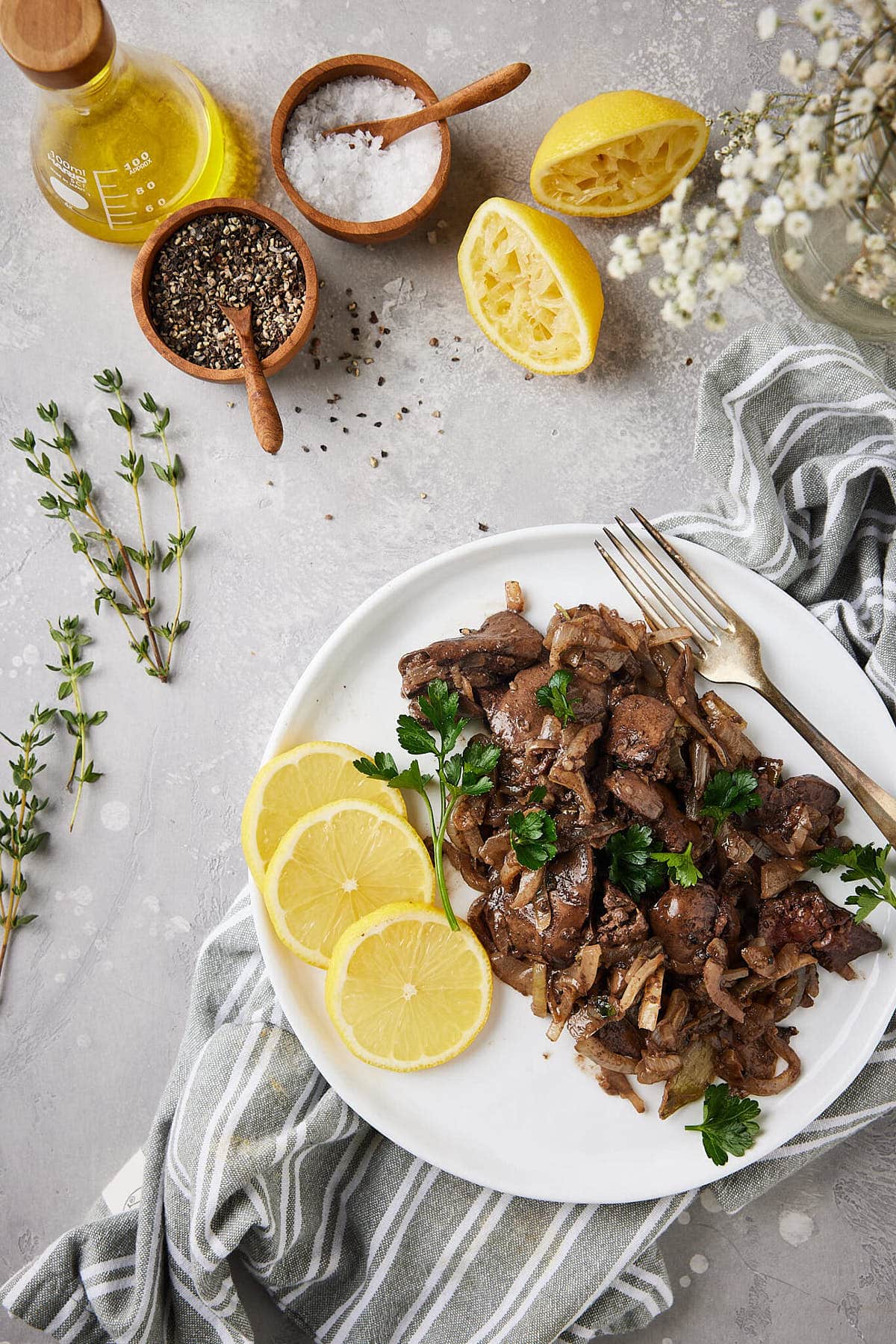 Chicken liver prepared on a plate with fresh herbs around it