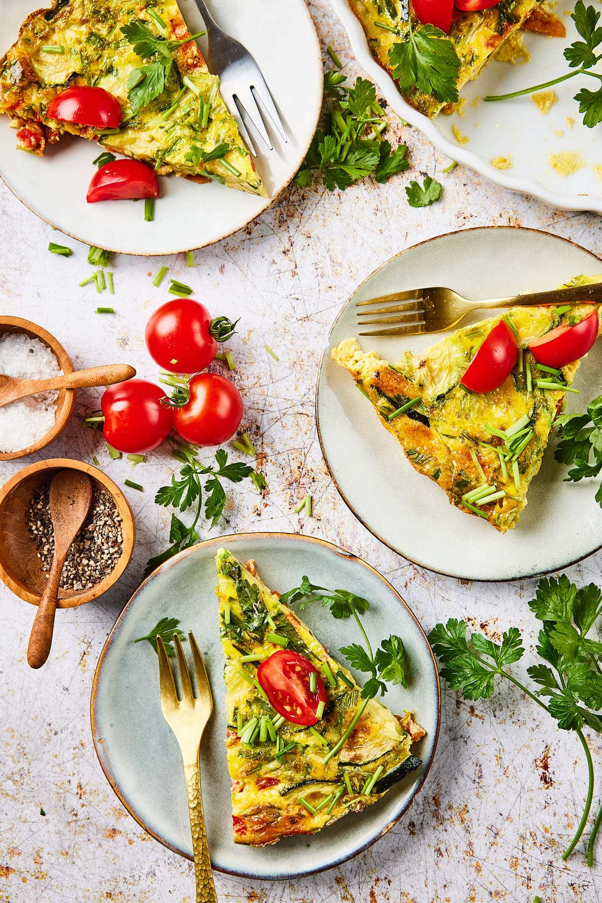 Zucchini quiche on plates with forks and salt and pepper
